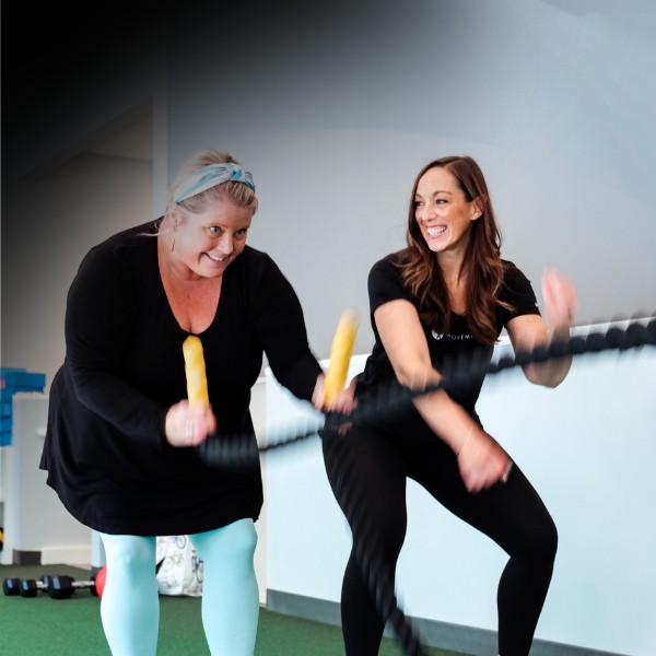 a movementx personal trainer working with a client on weight loss in a gym setting using rope exercises