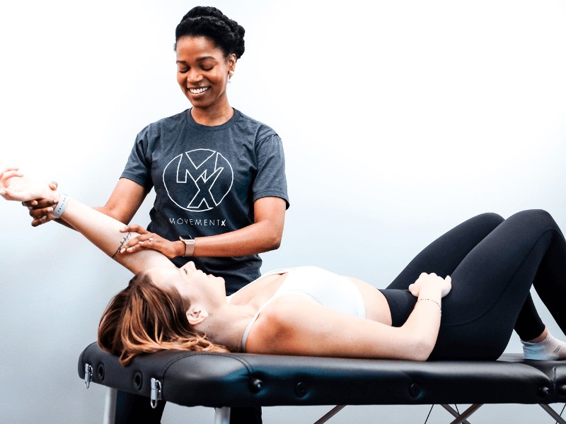 a movementx physical therapist providing shoulder treatment on a female patient in a bright clinic setting