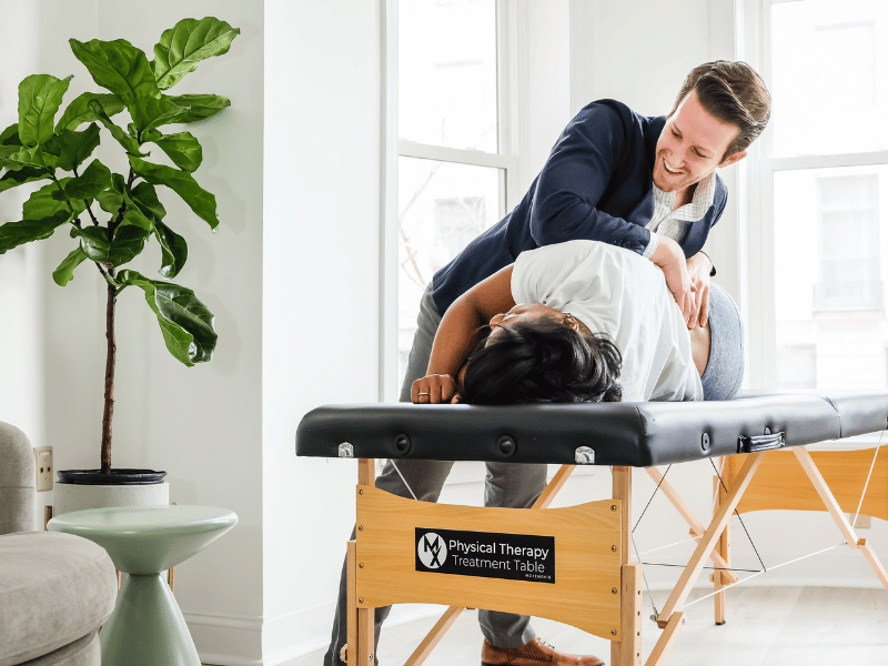 Josh D'Angelo, PT, DPT and Founder/CEO of MovementX treating a patient on a physical therapy treatment table in-home.