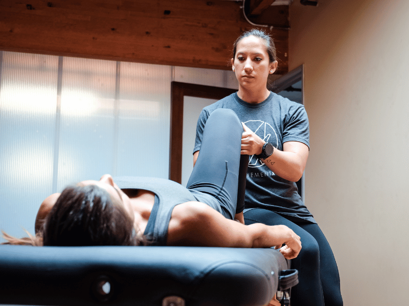 A MovementX provider helping a female athlete with knee pain in their home.