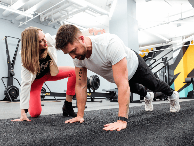 A MovementX provider, Stephanie Weyrauch, PT, DPT, helping a patient perform a challenging exercise during a session in a private gym.