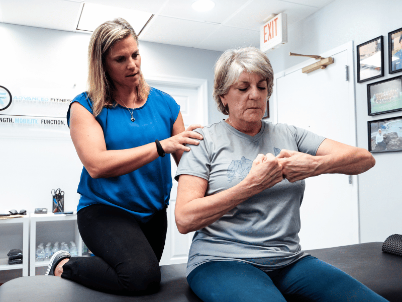 A MovementX provider helping a patient place their fists together.