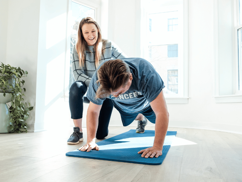 A MovementX provider helping a patient perform a straight-arm plank.