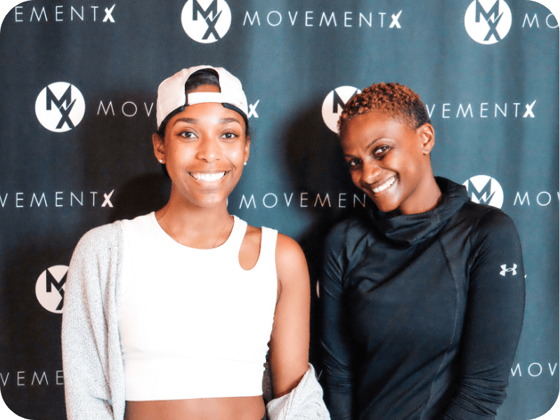 two newly hired movementx physical therapists who are excited about their new PT jobs in maryland in front of a movementX sign