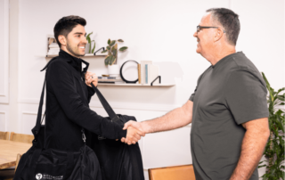 A movementx physical therapist in orange county shaking hands with a new patient in a home setting