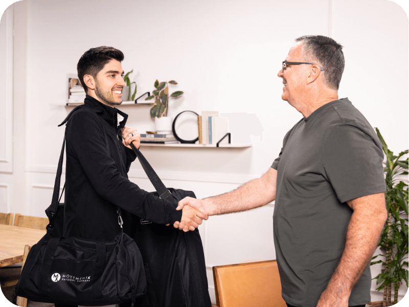 A movementx physical therapist in orange county shaking hands with a new patient in a home setting