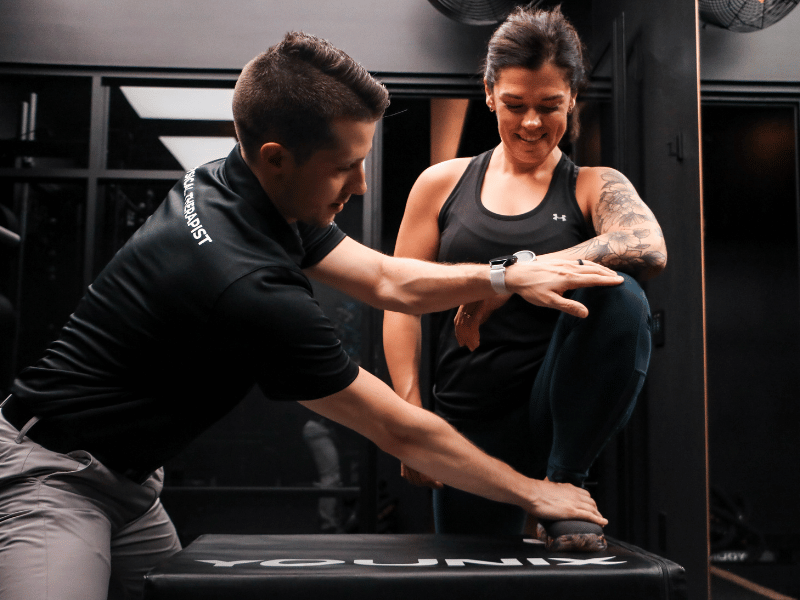 Adam Kays, PT, DPT helping a patient perform a correct box step up in a treatment session.