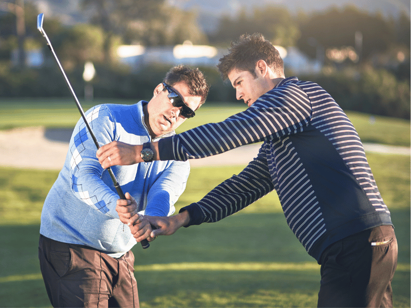 A MovementX physical therapist giving swing instruction to a golfer on the course in the DMV area.