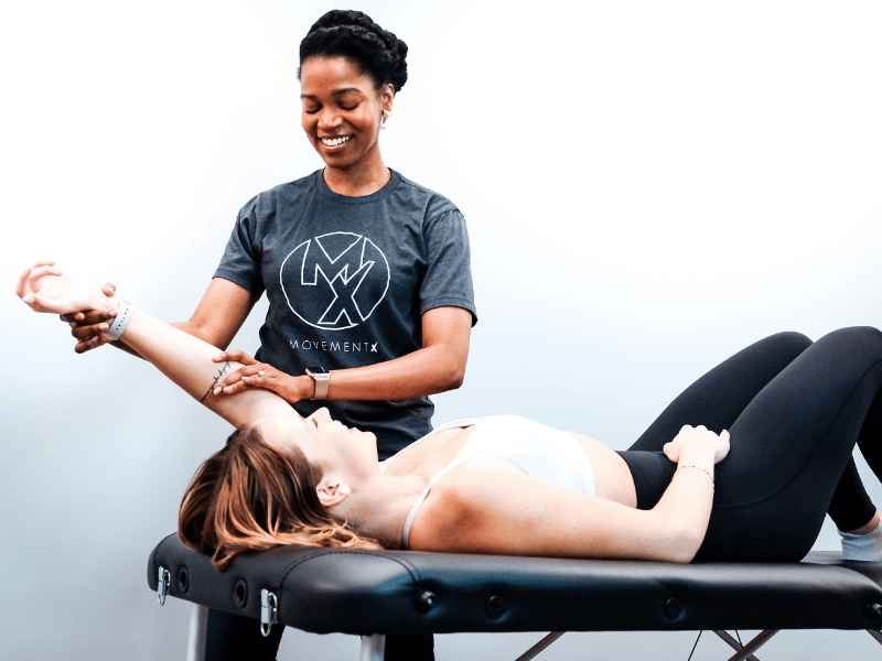 Dr. Diana Jean-Mary assisting a patient on a treatment table.