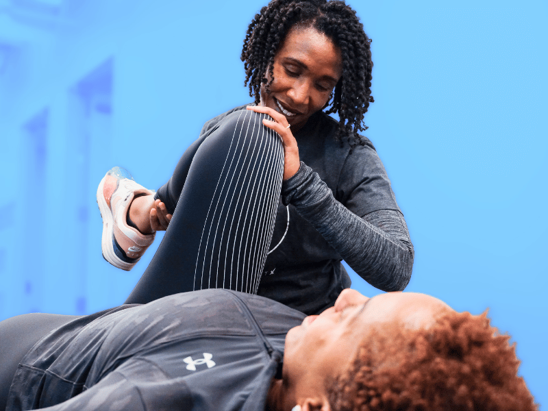 A MovementX Provider helping a patient through a set of hip mobility assessments on a treatment table in Austin, Texas.