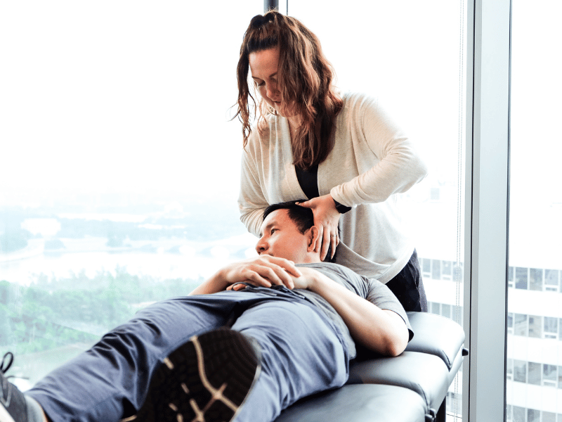 A MovementX physical therapist helping a patient stretch and mobilize their neck during a treatment session.