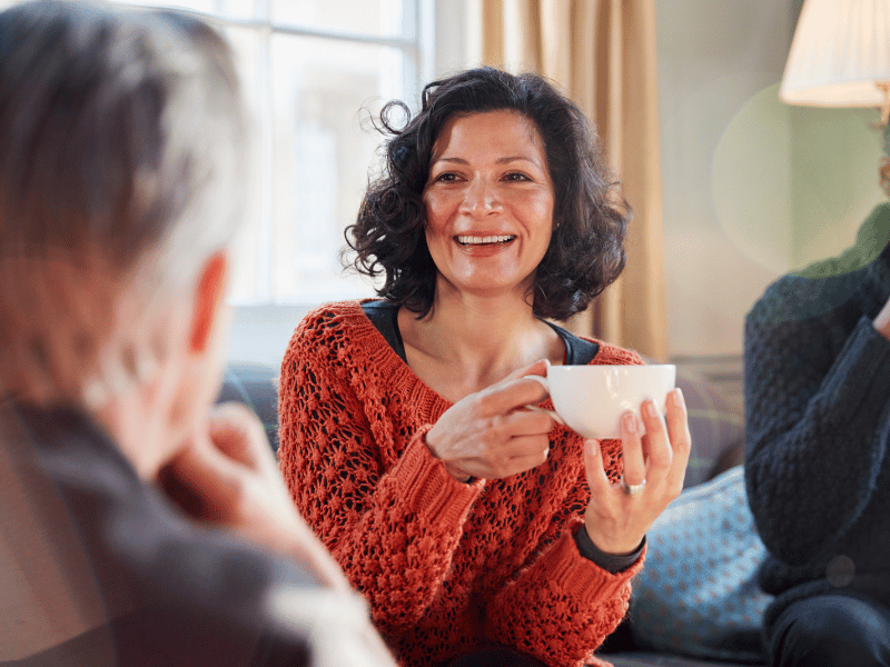 A middle aged woman enjoying a coffee with her friends.