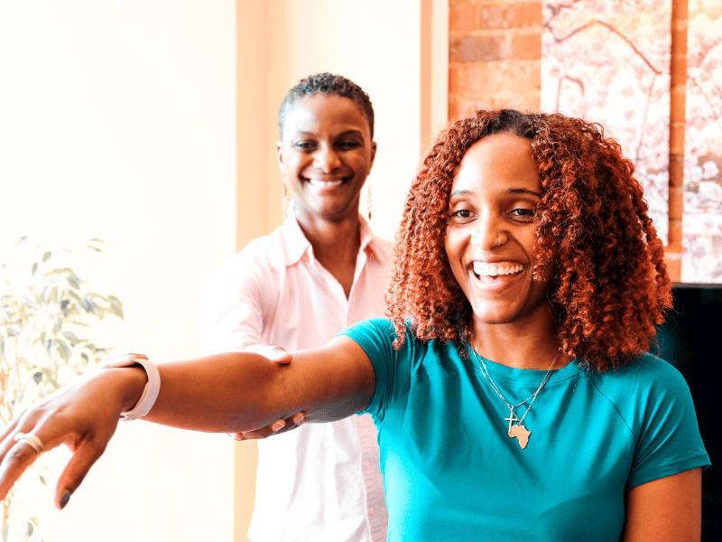 Imani Mack, PT, DPT helping a patient maneuver their rotator cuff through a physical therapy session.