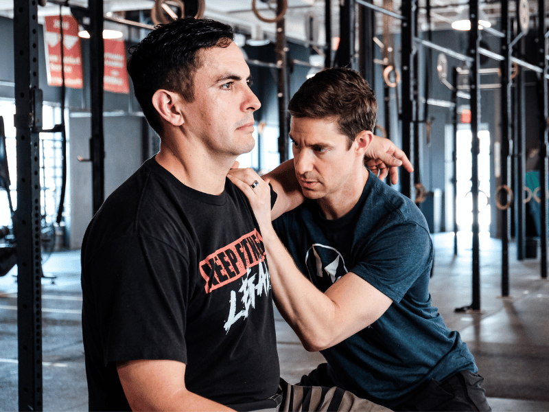 MovementX provider Dan Alcorn, PT, DPT assisting a patient with shoulder mobility in a gym in Northern Virginia.