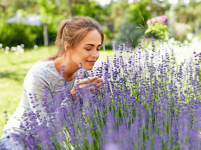 A woman leaning down to smell the flowers in a well tended garden.