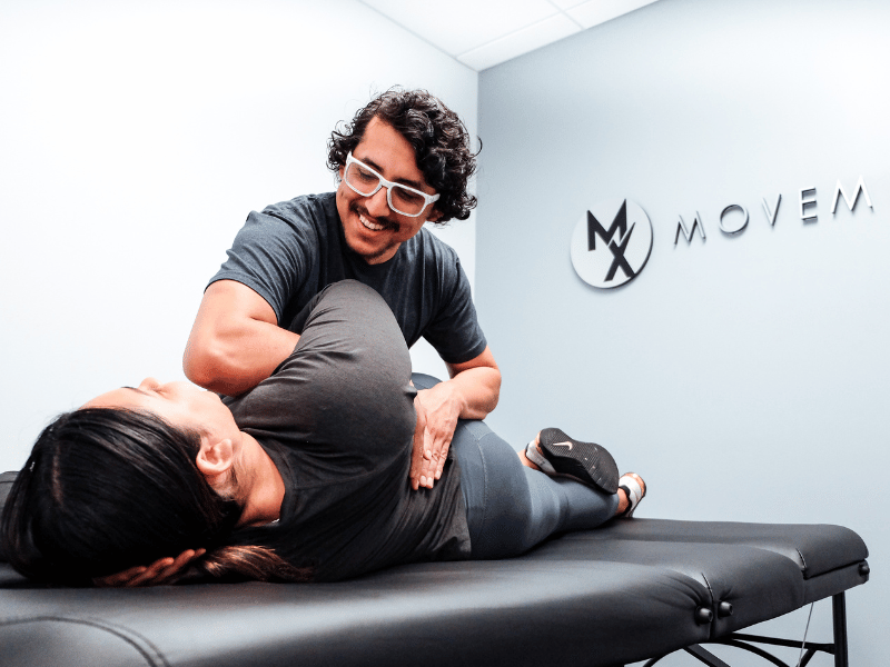 Rich Ortiz, PT, DPT helping a patient through a spinal flexion assessment on a treatment table in Washington, D.C.