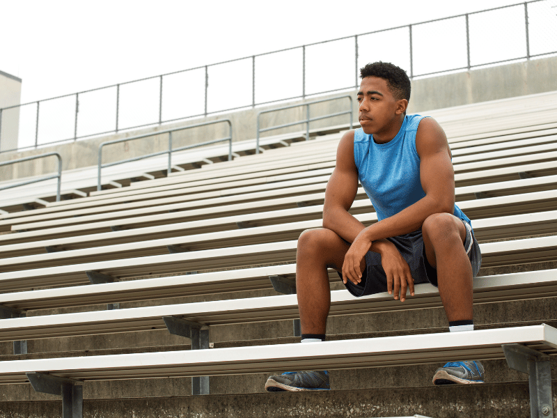 A runner sitting on bleachers, thinking.