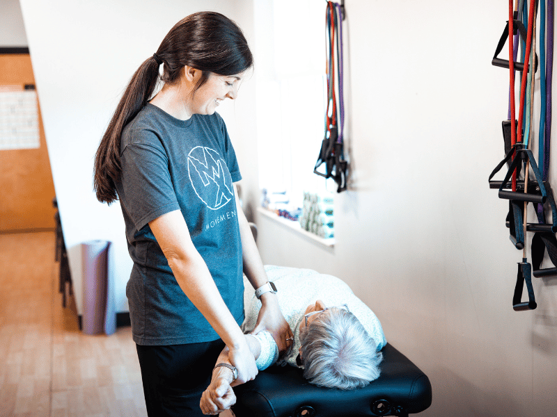 A MovementX physical therapist helping a patient mobilize their shoulder during an in-home treatment session.