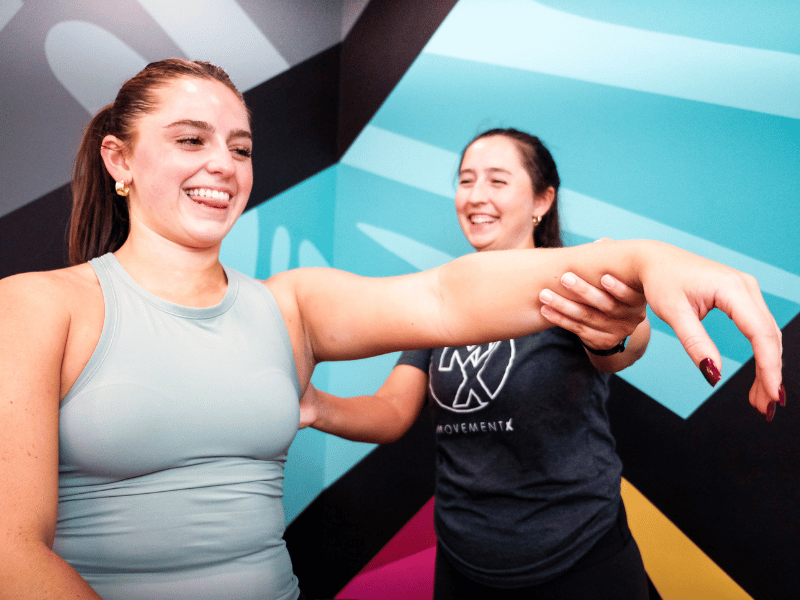 A MovementX physical therapist helping a patient move through front shoulder raises.