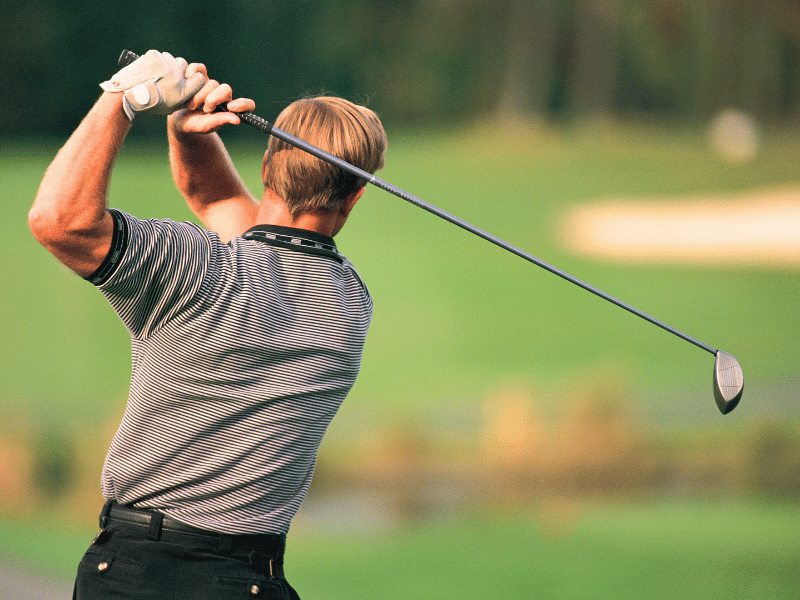 A golfer finishing their swing after developing better rotational power from physical therapy.