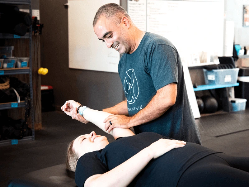 a movementx physical therapist in cary north carolina working with a female patient for shoulder pain treatment in a crossfit gym setting