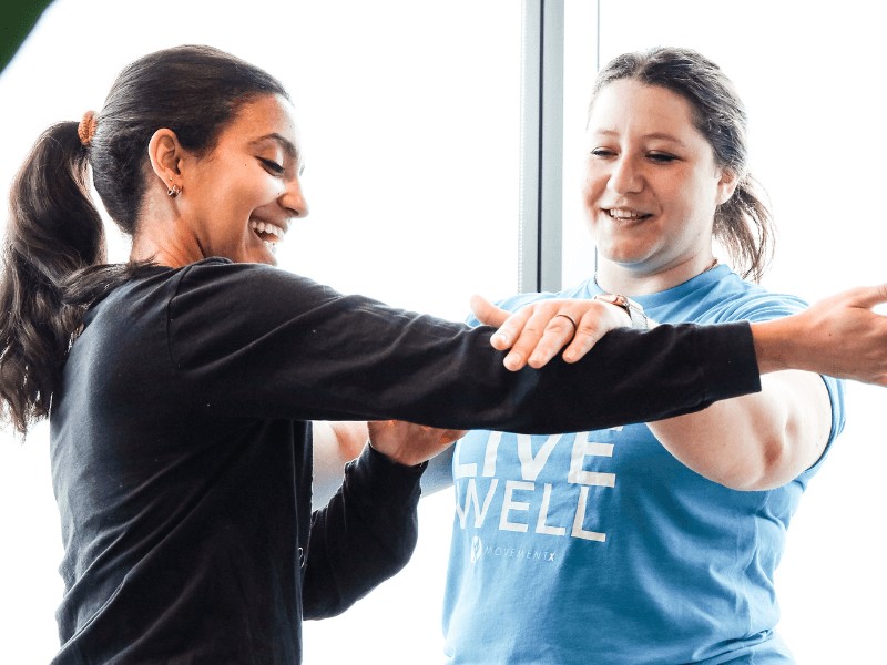 a female movementx physical therapist treating a patient with neck pain in a bright clinic setting