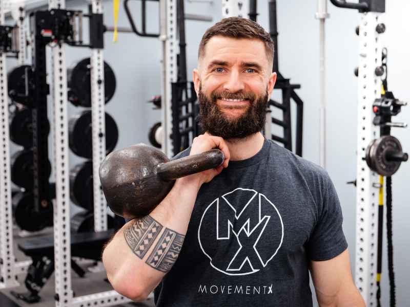 Dr. Matt Syzmanski front rack carrying a kettlebell in a gym in Rocky Hill, Connecticut