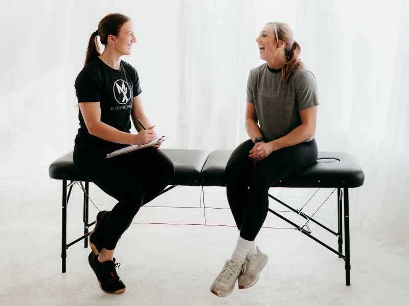 Cali Pyzdrowski, PT, DPT consulting with a patient in North Carolina while sitting on a treatment table.
