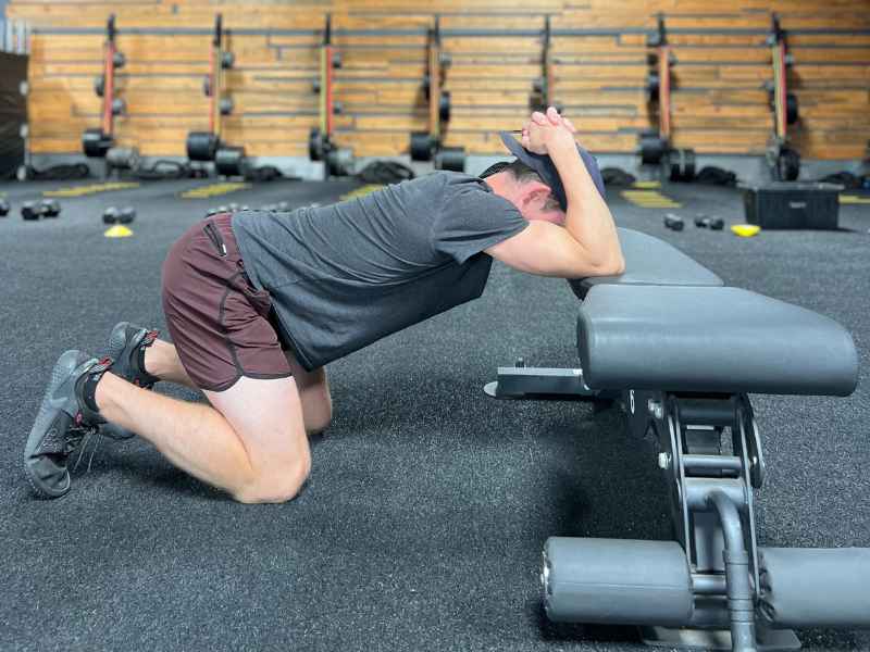 Dr. Chris MonPere performing a kneeling lat stretch in Orange County to prep for the Hyrox competition