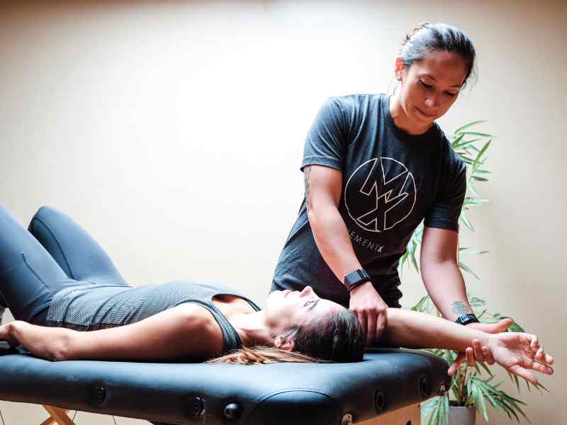 Jessica Crowder, PT, DPT in Huntington Beach helping a patient assess their shoulder mobility on a treatment table.