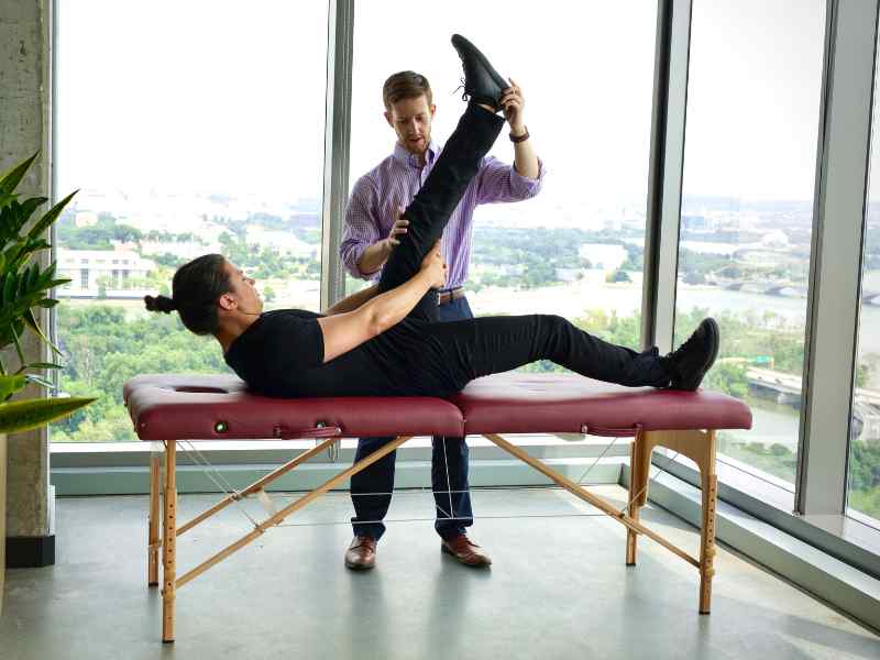 Josh D'Angelo, PT, DPT and CEO of MovementX adjusting a patient on a treatment table in their office.