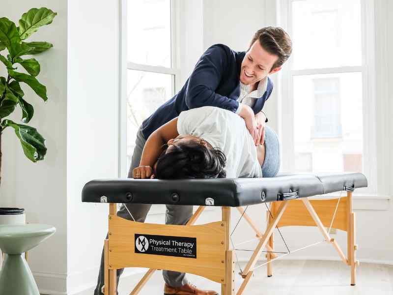 Josh D'Angelo, PT, DPT and CEO of MovementX adjusting a patient on a treatment table in-home.