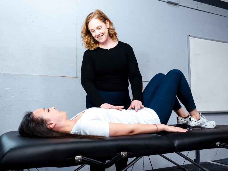 McCaul Butcher, PT, DPT helping a patient with pelvic floor activation on a treatment table.