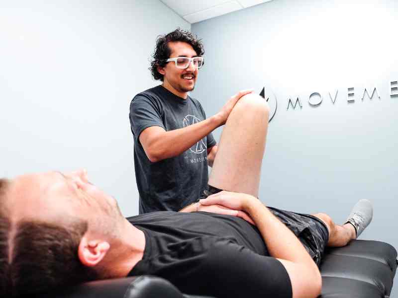 Dr. Rich Ortiz helping a patient with knee flexion in a MovementX co-treatment space in Washington DC.