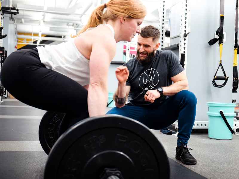 A MovementX physical therapist (Matt Syzmanski) helping a patient work through a deadlift progression for back pain.