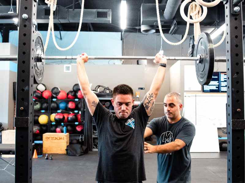 MovementX provider Romin Ghassemi, PT, DPT helping a patient work through an Olympic lift in a gym in North Carolina.