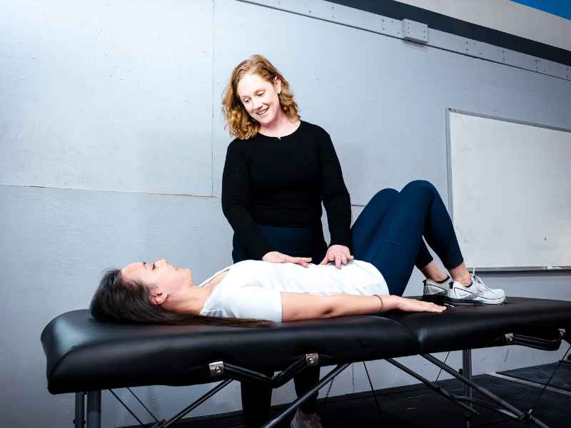 MovementX provider McCaul Butcher, PT, DPT helping a patient through a pelvic health assessment on a treatment table.