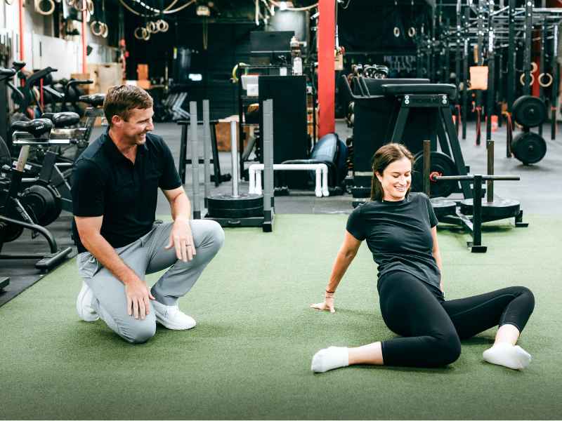 Tyler Eubanks, PT, DPT helping a patient through a set of hip opening golf exercises in Durham, NC during a session.