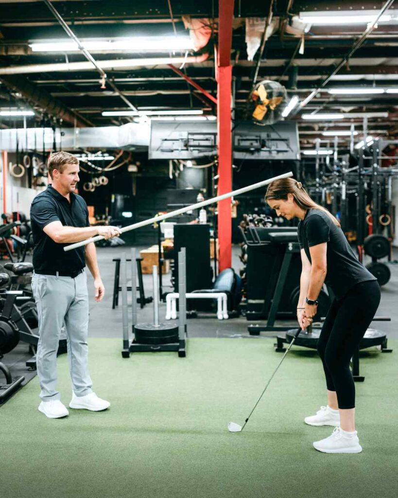 Tyler Eubanks, PT, DPT helping a patient through a posture exercise for golf during a session in Durham, NC.