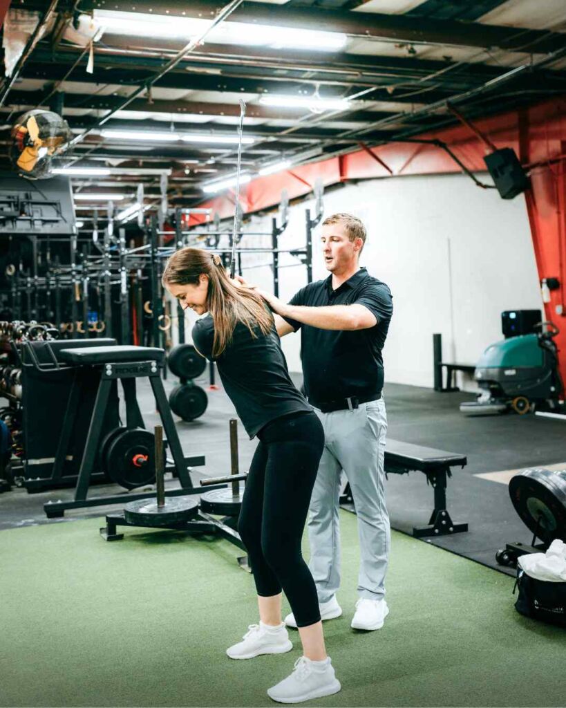 Tyler Eubanks, PT, DPT helping a patient through a golf swing exercise during a session in Durham, NC.