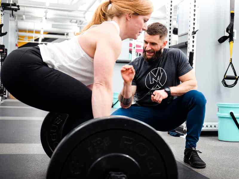 A MovementX provider helping a patient strengthen a deadlift progression.