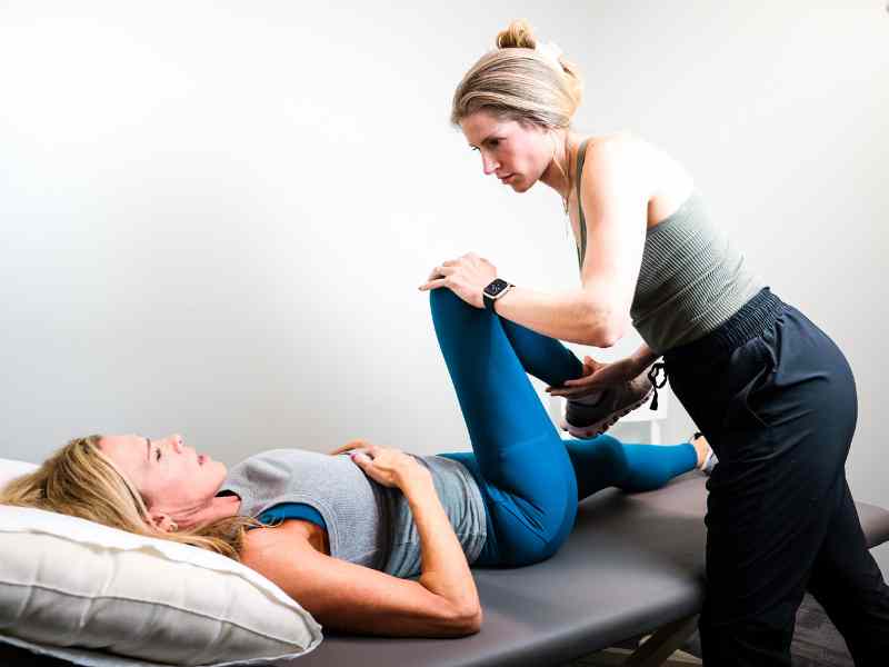 A MovementX provider, Ciara Puderbaugh PT, DPT helping a new mother strengthen and stretch during a treatment session.