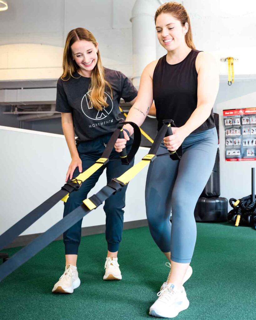 Natalie de Selding, PT, DPT helping a patient through a sled pull during a physical therapy session.