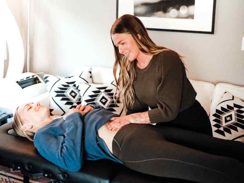 A MovementX provider helping a female patient navigate and understand abdominal and pelvic pain during an in-home session.