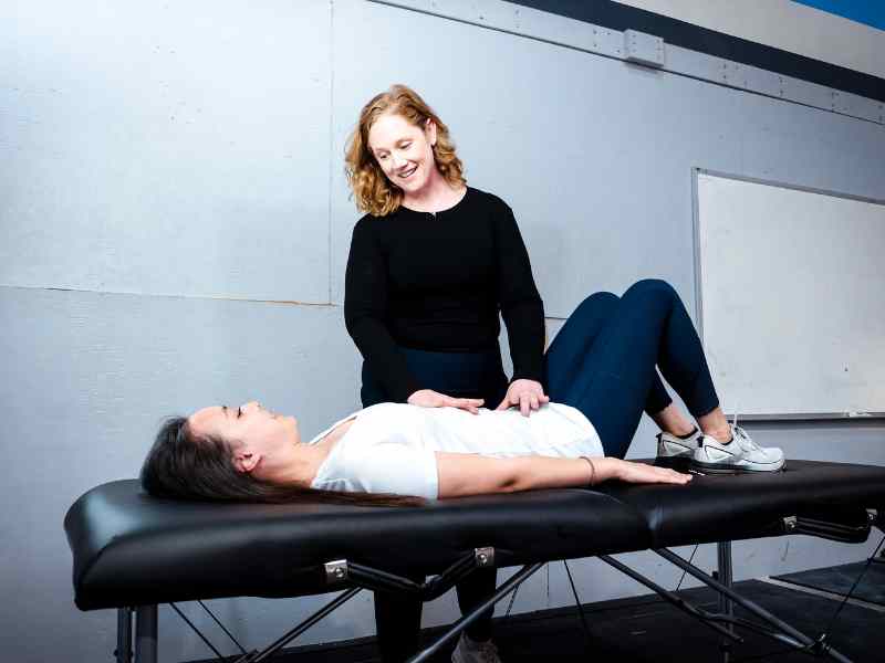 MovementX physical therapist McCaul Butcher helping a patient assess their pelvic health on a treatment table during an in-home session in Leesburg, Virginia.