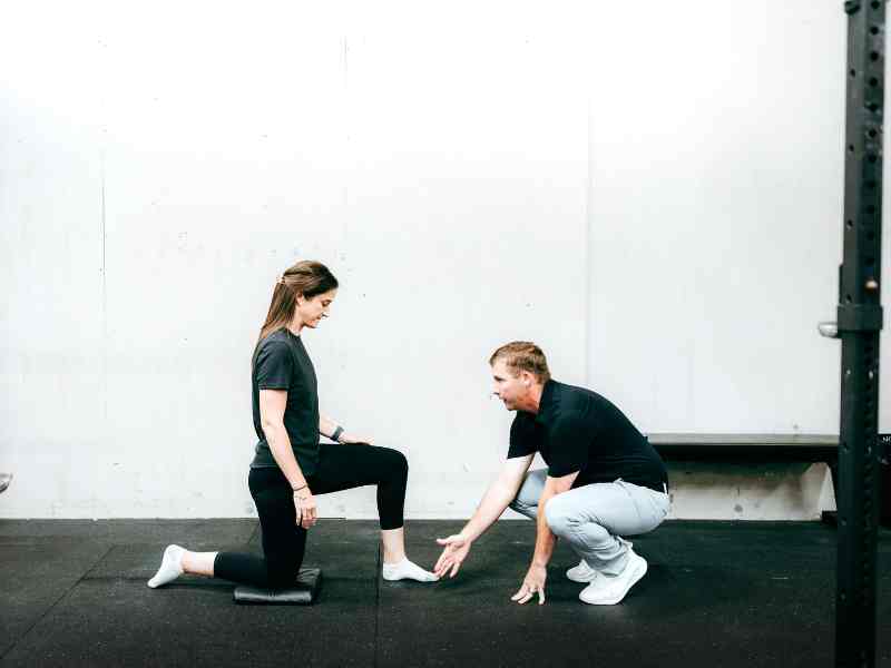 MovementX Physical Therapist, Doctor Tyler Eubanks helping a patient do hip flexor stretches in a gym in Raleigh, North Carolina