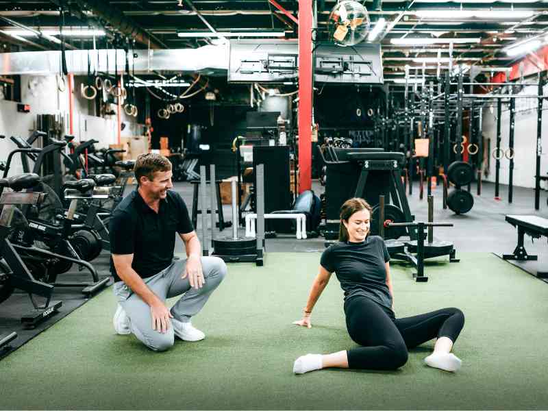 MovementX Physical Therapist, Doctor Tyler Eubanks helping a patient do hip 90-90s in a gym in Raleigh, North Carolina