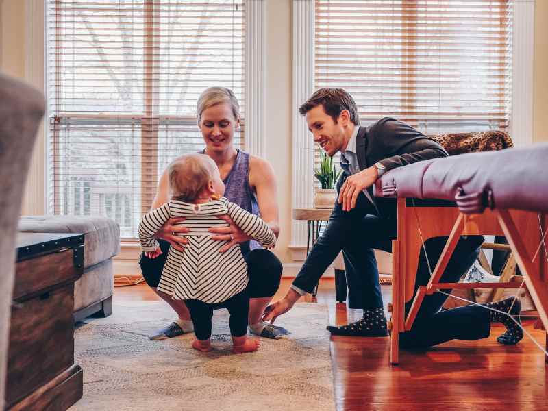 A mother, a baby, and a MovementX physical therapist squatting on the floor in the patient's home.