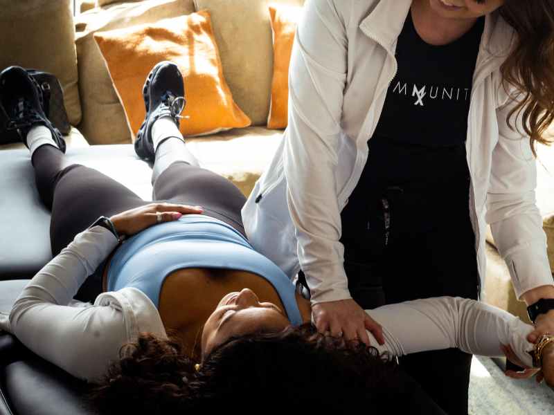 MovementX provider Taylor Morgan, PT, DPT helping a mature patient assess her shoulder mobility during an in home physical therapy session.