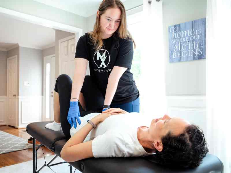 MovementX physical therapist Morgan Groover, PT, DPT working with a patient on a treatment table to test abdominal pressure and sensitivity.